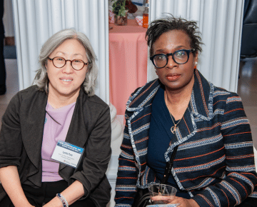 Two people wearing glasses and business attire, posing for a photo.